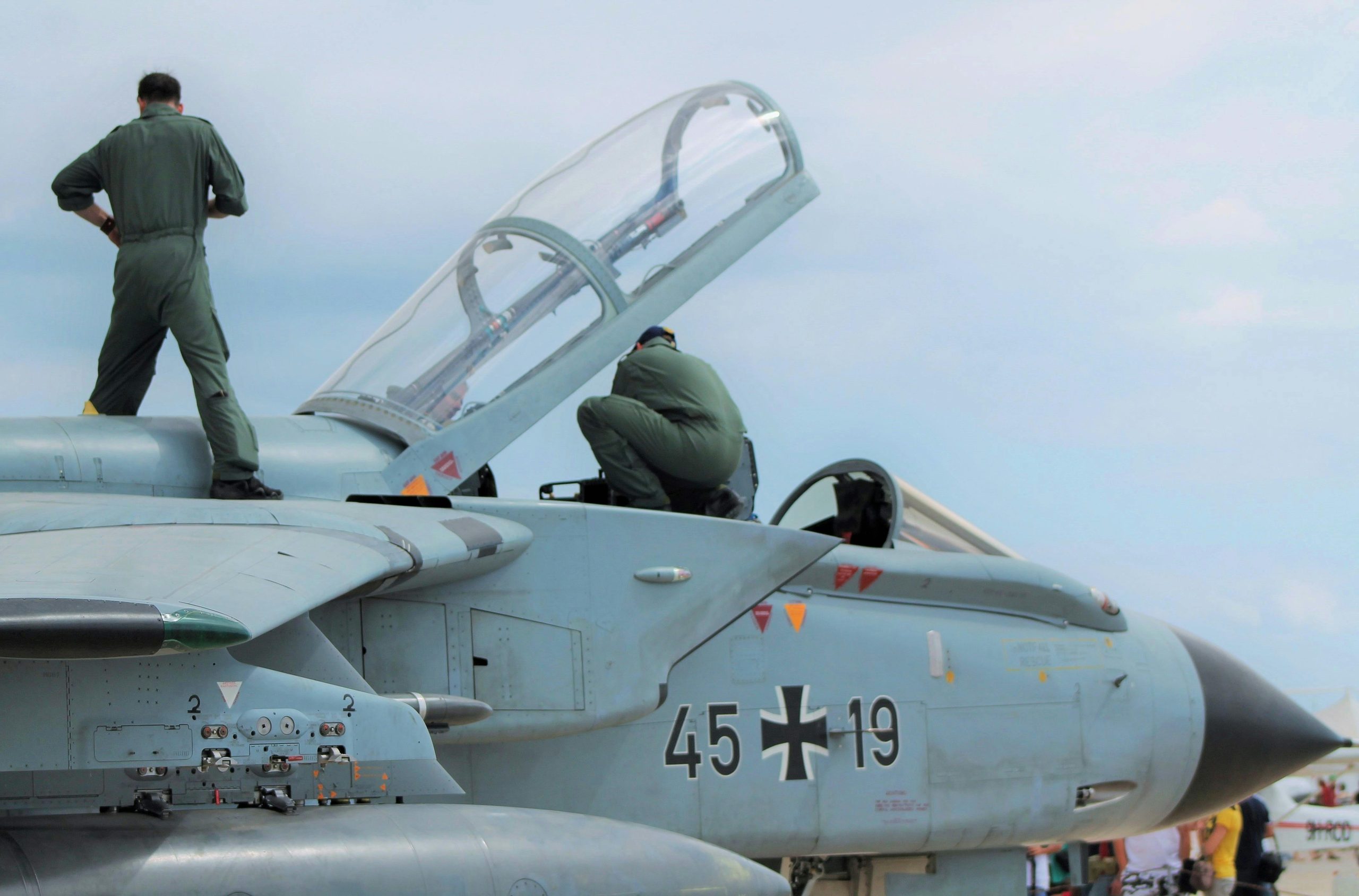 Free Low angle of unrecognizable male pilots in uniforms standing on aged gray multirole combat aircraft before flight against cloudy sunset sky Stock Photo