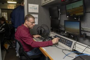 eVTOL urban air mobility 2026 — NASA researcher Dennis Iannicca adjusts a control board in the Mobile Operations Facility to gather Automatic Dependent Surveillance-Broadcast signal data at NASA’s Armstrong Flight Research Center in Edwards, Cal (AFRC2024-0145-25)