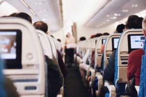 Flight attendant walking the aisle of a full airliner cabin