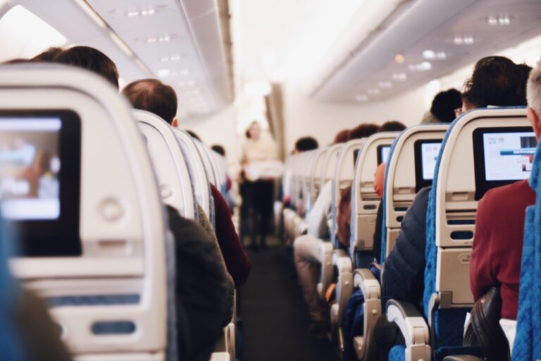 Flight attendant walking the aisle of a full airliner cabin