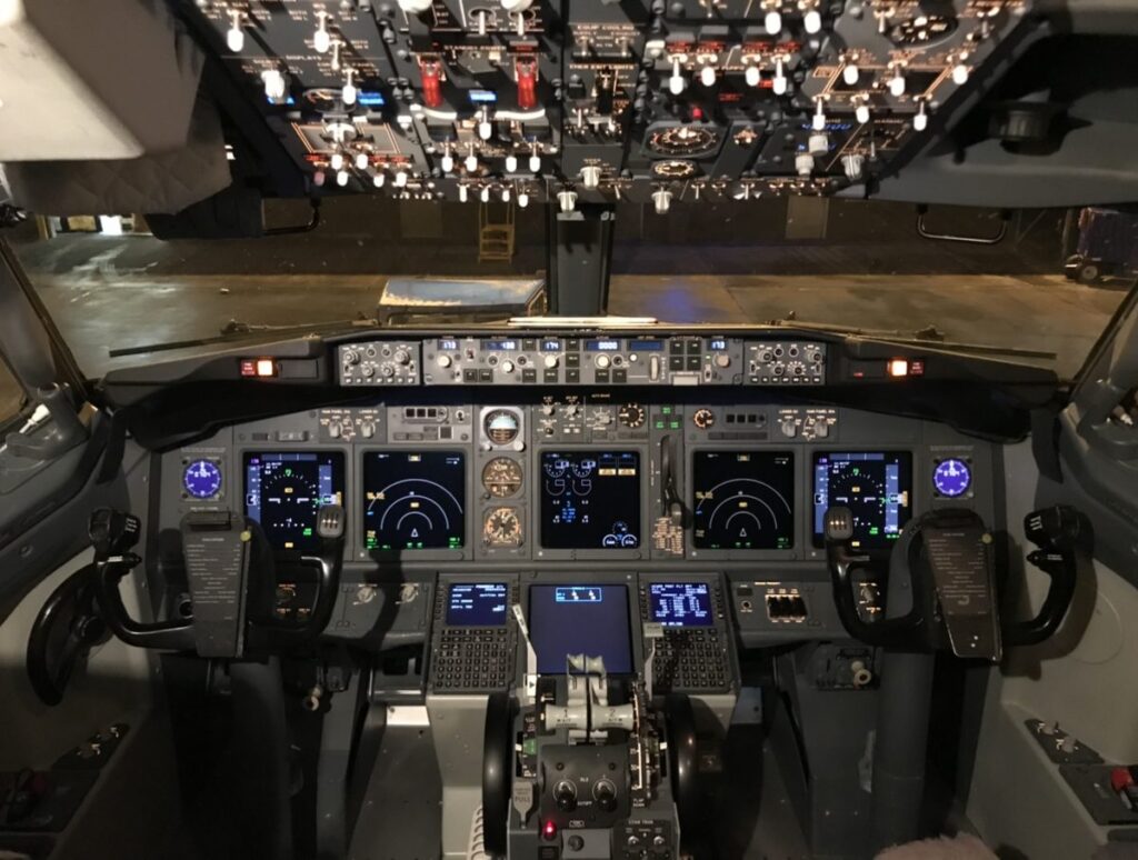 What Pilots Are Actually Saying: Every Phrase You Hear, Decoded Boeing 737 flight deck showing the radio and audio control panels between the pilot seats
